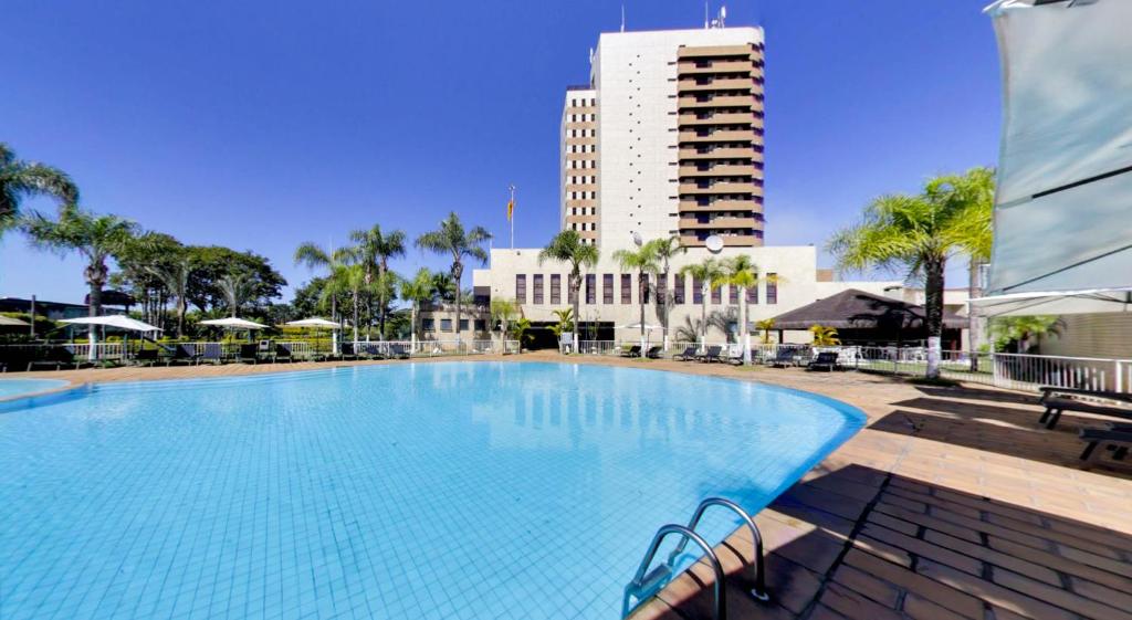una gran piscina con un edificio alto en el fondo en Marques Plaza Hotel, en Pouso Alegre