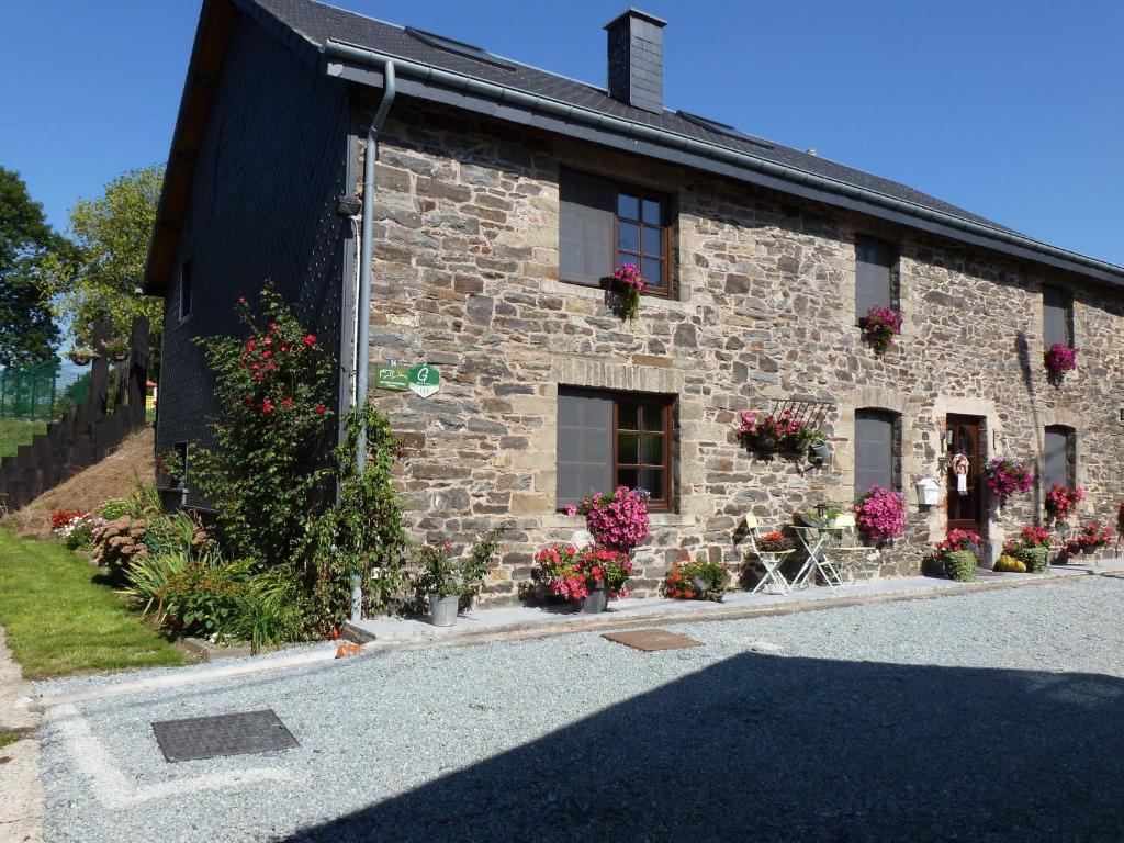 a stone house with flowers on the side of it at Restored cottage in an old Ardennes farmhouse in Nimbermont