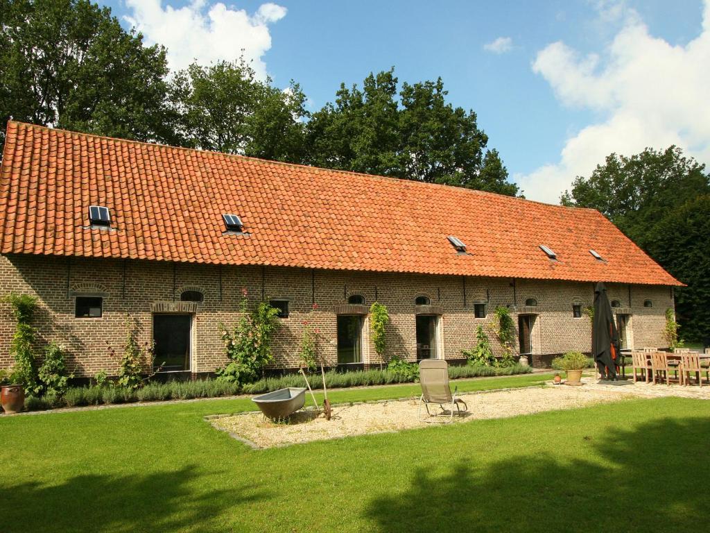 ein großes Backsteingebäude mit orangefarbenem Dach in der Unterkunft Rural holiday home in former stables in Beernem