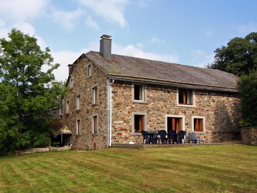 een oud stenen huis met tafels en stoelen op een gazon bij Quaint Cottage in Egb mont with Garden in Exbomont