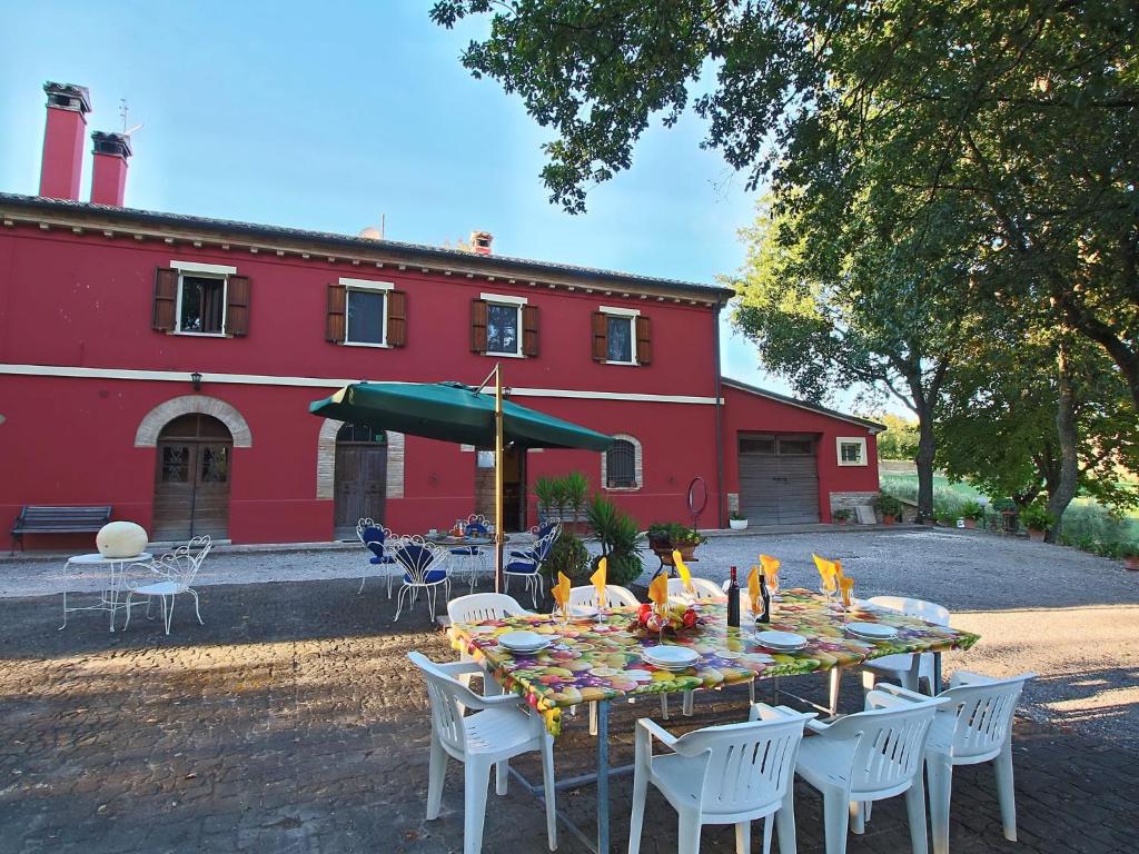 a table with a green umbrella in front of a red building at Belvilla by OYO Casa Lella in Serrungarina