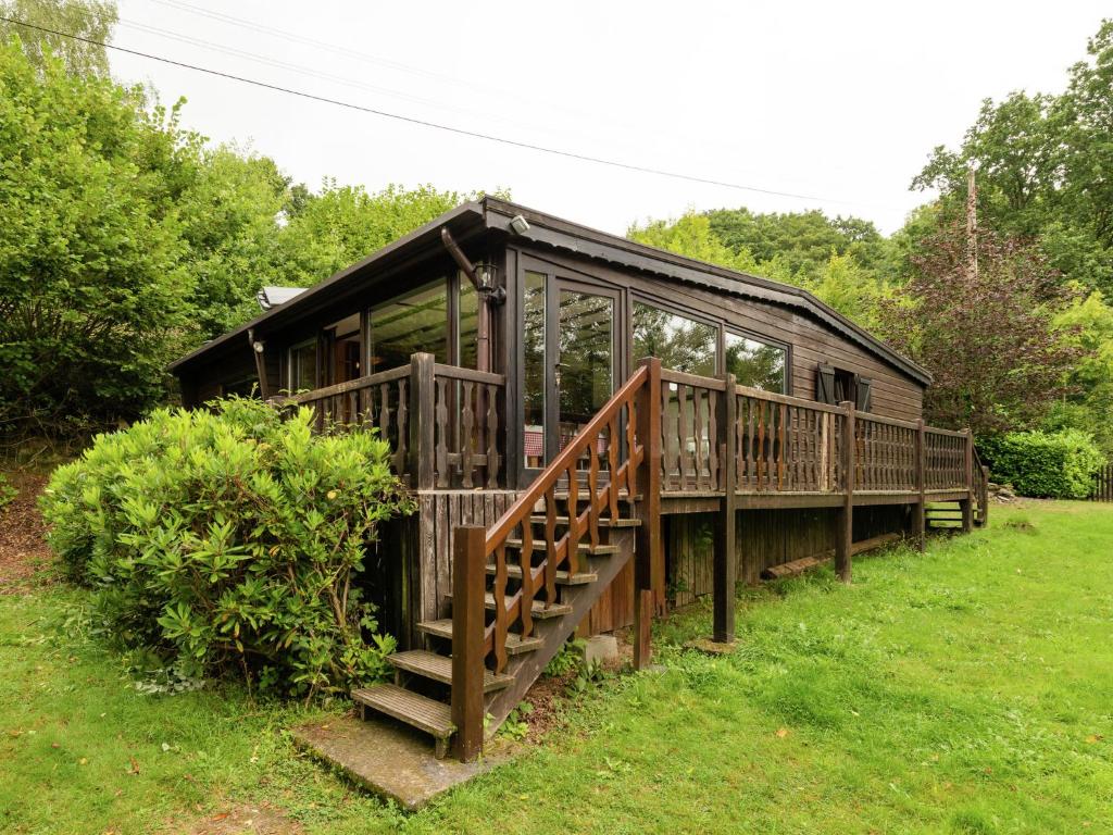 ein großes Holzhaus mit einer Treppe im Gras in der Unterkunft Sympathic Chalet not far from La Roche en Ardennes in La-Roche-en-Ardenne