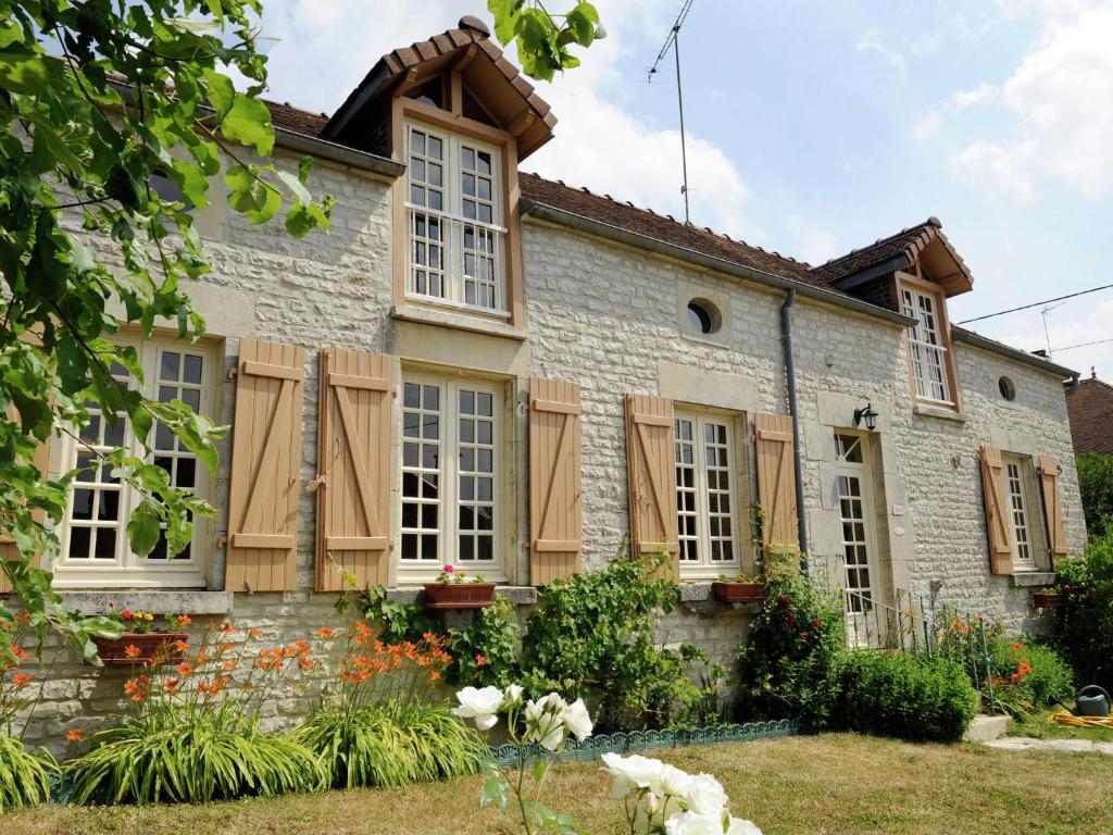 a house with wooden shutters and a yard at Country cottage with enclosed garden in Bligny in Bligny