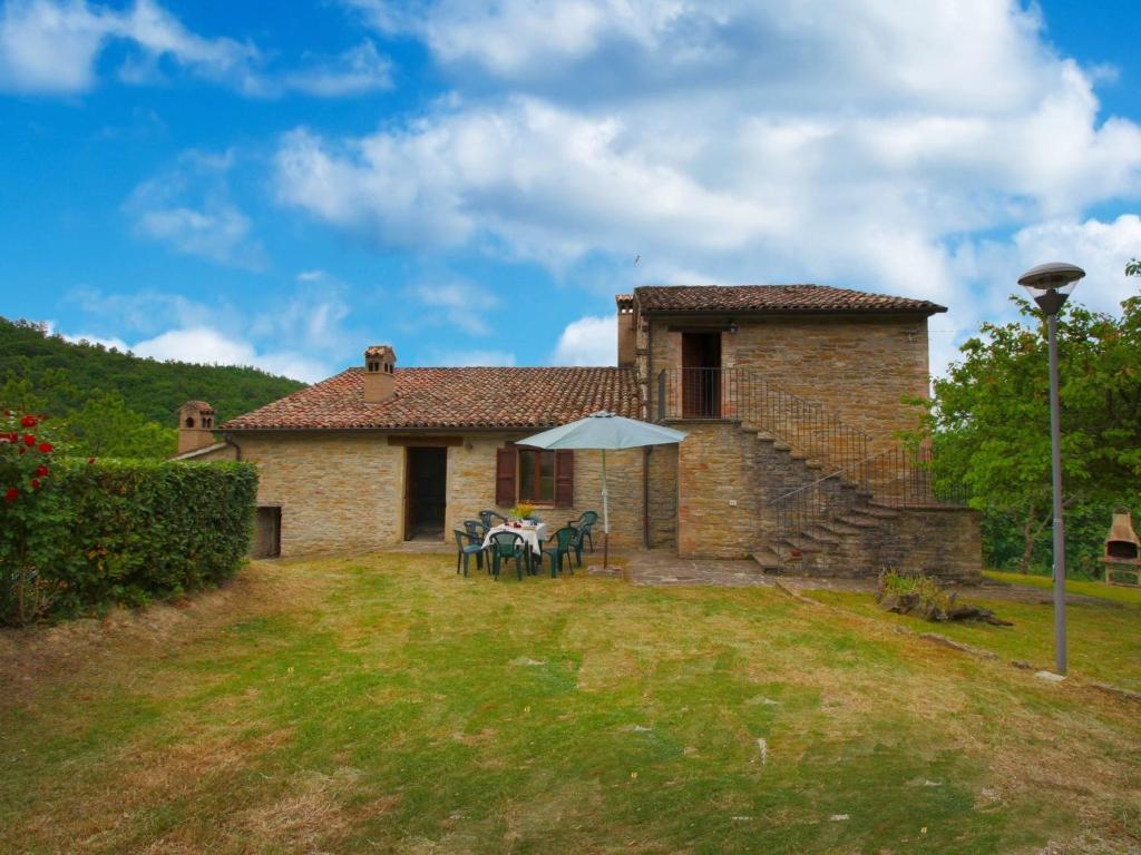 a stone house with a table and an umbrella at Belvilla by OYO Cal Bianchino in Mercatello sul Metauro