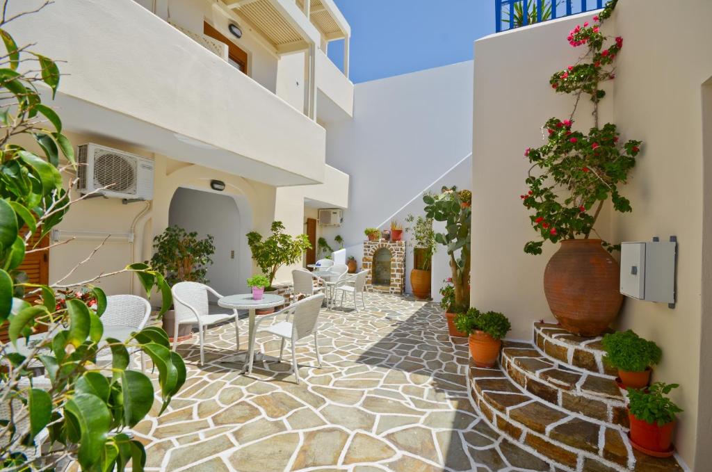 un patio con mesas, sillas y macetas en Margo Studios en Naxos