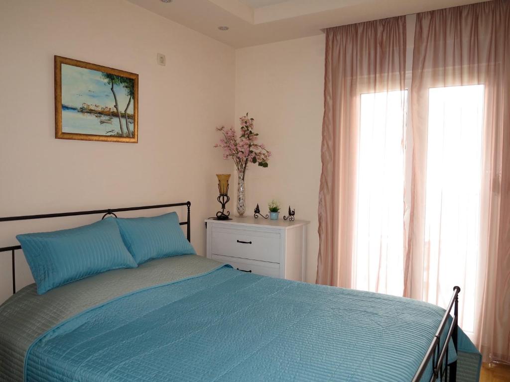 a bedroom with a blue bed and two windows at Apartment Verdan in Bar