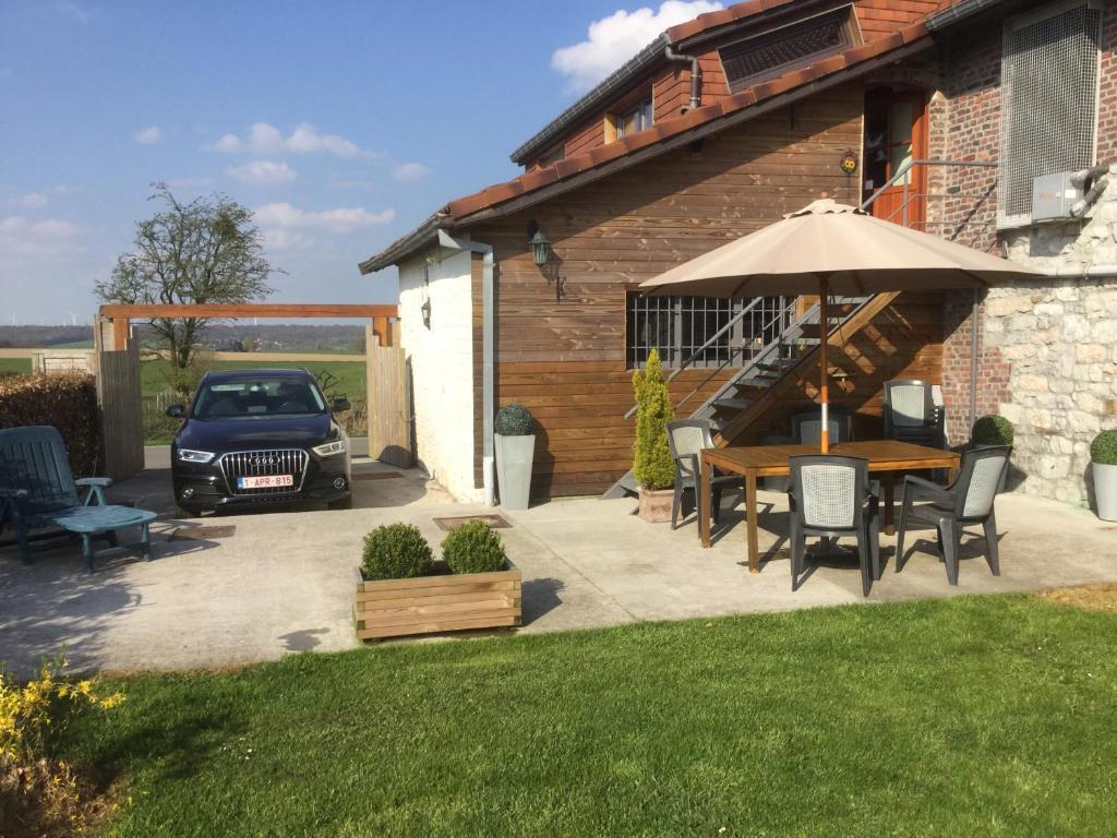 a patio with a table and an umbrella and a car at "A la petite éolienne" in Froid-Chapelle