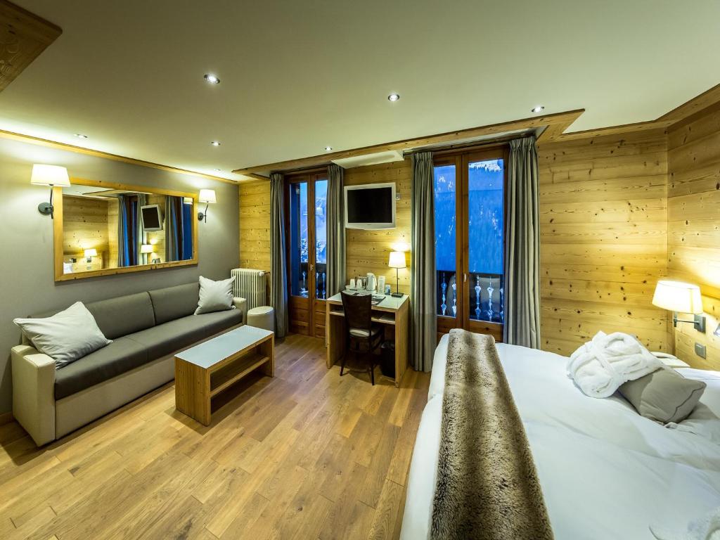 a bedroom with a bed and a couch and a desk at Fleur De Neige Hôtel in Châtel