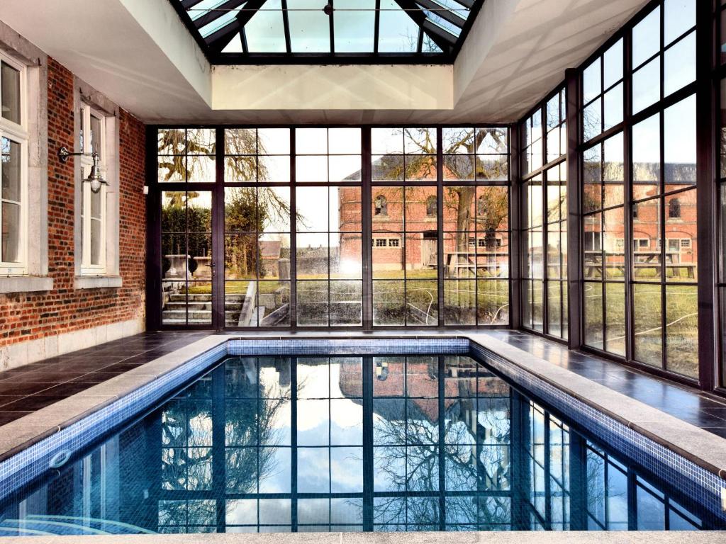uma piscina interior numa casa com janelas em Luxurious Mansion with indoor pool and Sauna em Mesnil-Saint-Blaise