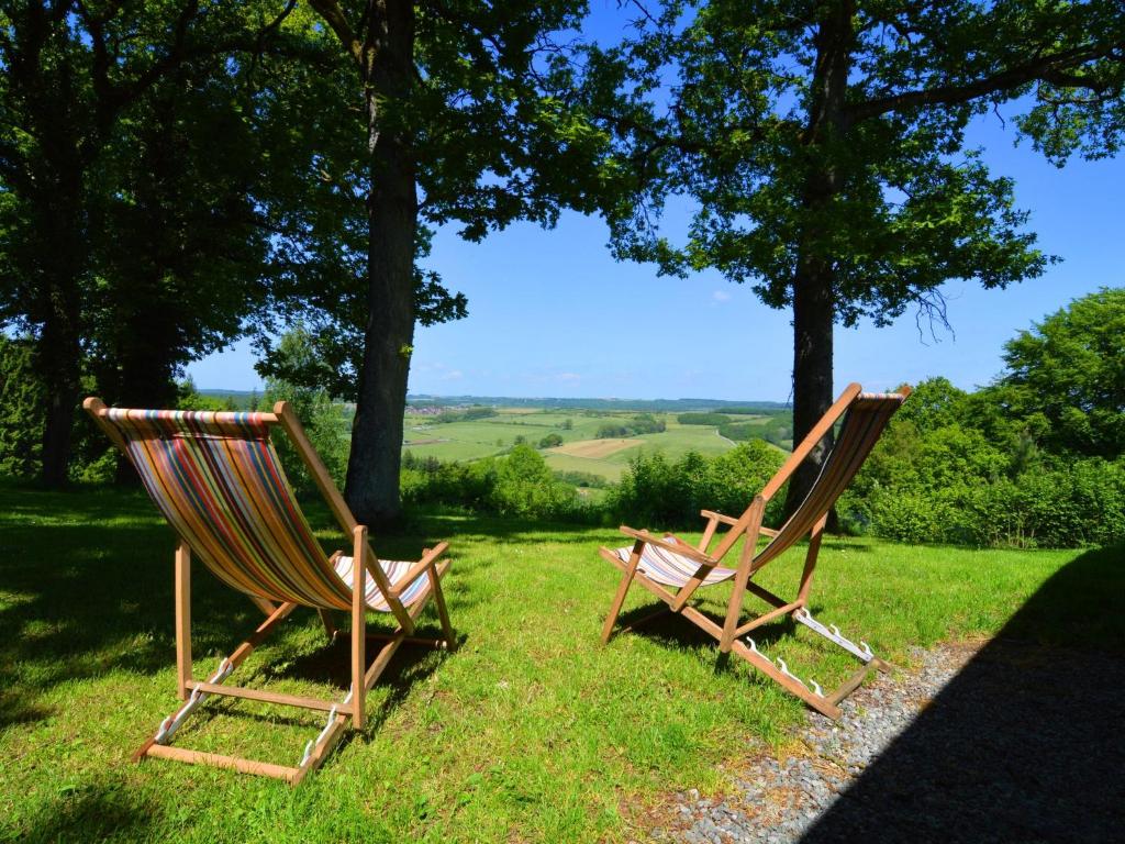 two rocking chairs sitting on the grass in a field at Modern Chalet with Private Tennis Court in Humain in Humain