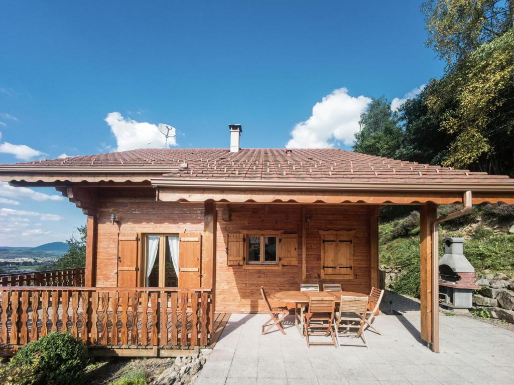 a house with a table and chairs on a patio at Beautiful chalet with sauna and views of Vosges in Anould