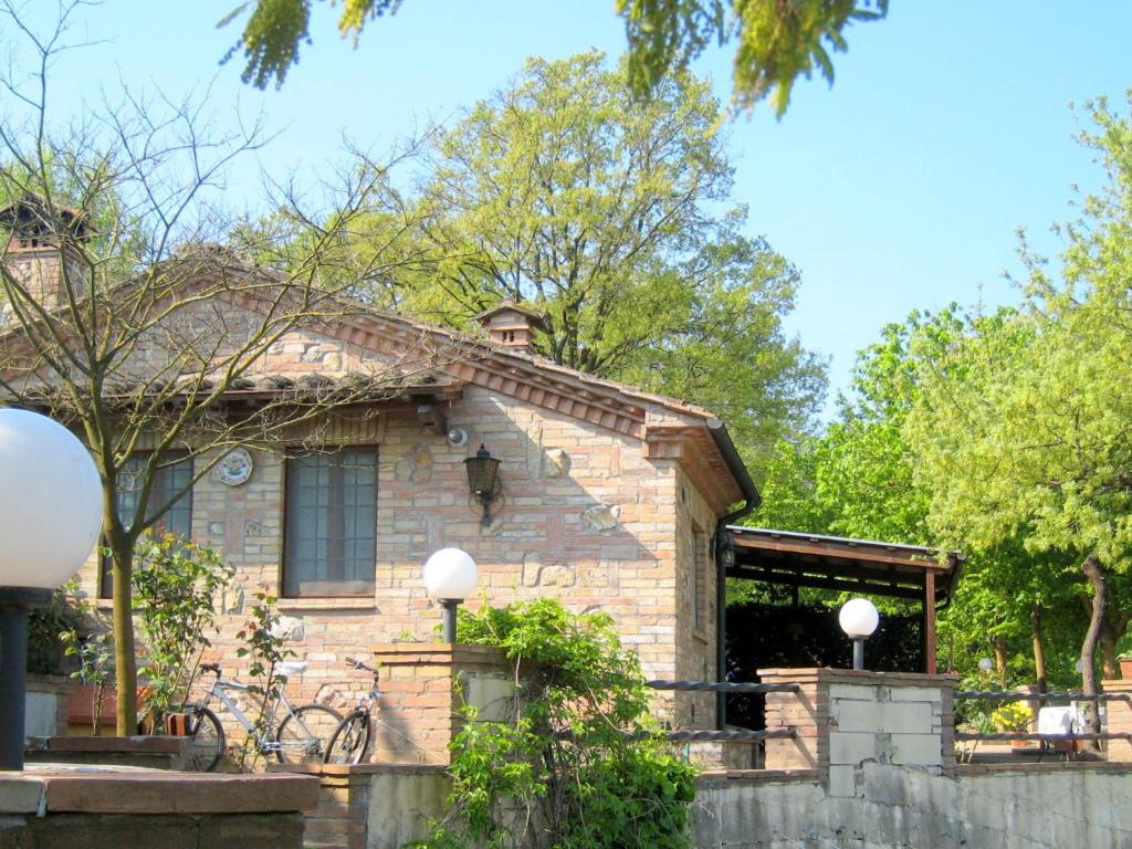 a brick house with a porch and trees at Belvilla by OYO Casa Gioia in Chiusdino