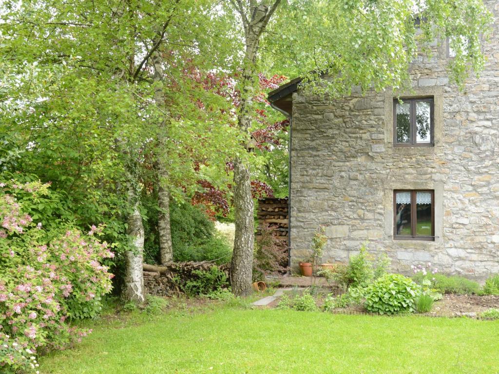 una casa de piedra en un patio con árboles en Former farmhouse in a quiet village, en Manhay