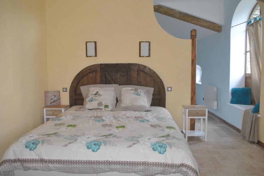 - une chambre avec un grand lit et une tête de lit en bois dans l'établissement Domaine de la Poyat, à Légny