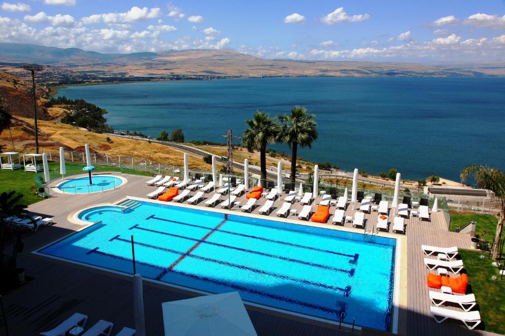 een zwembad met stoelen en uitzicht op het water bij Golan Hotel in Tiberias