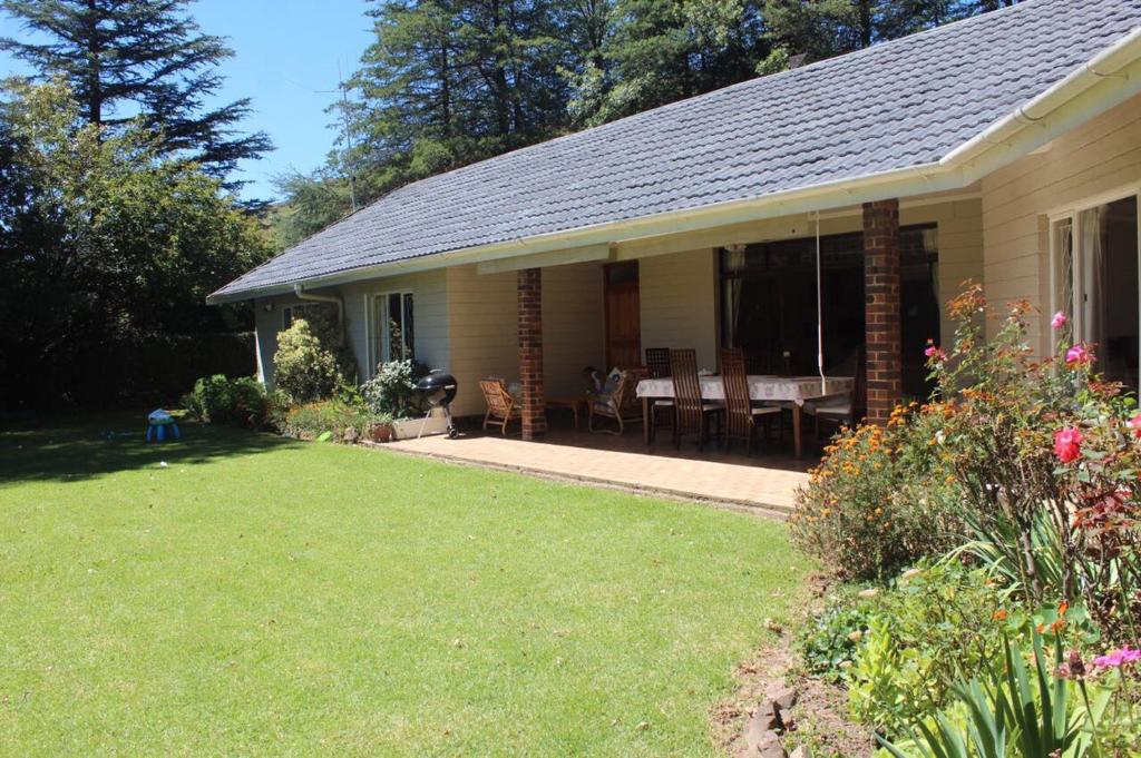 a house with a yard with a table and chairs at Hawley House in Underberg
