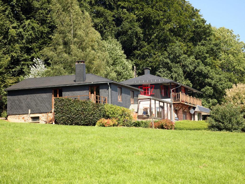 een groot huis op een heuvel met een grasveld bij Attached gite on the edge of the forest in Trois-Ponts