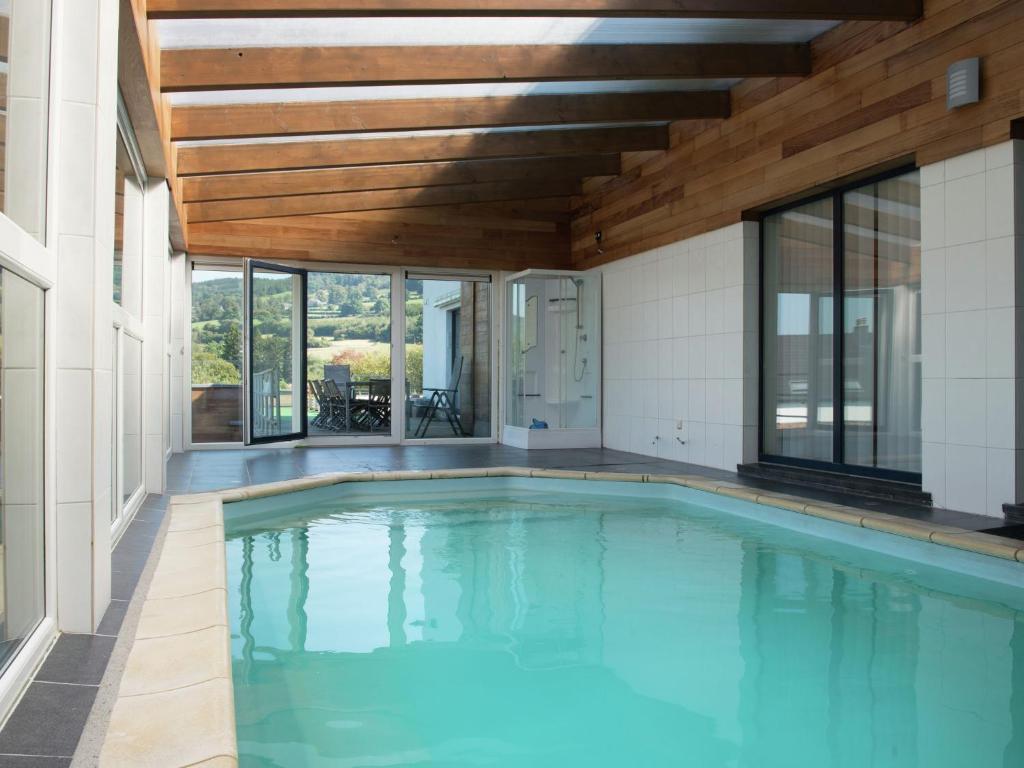 an indoor swimming pool with a wooden ceiling and windows at Beautiful loft in Stoumont with sauna and indoor pool in Stoumont