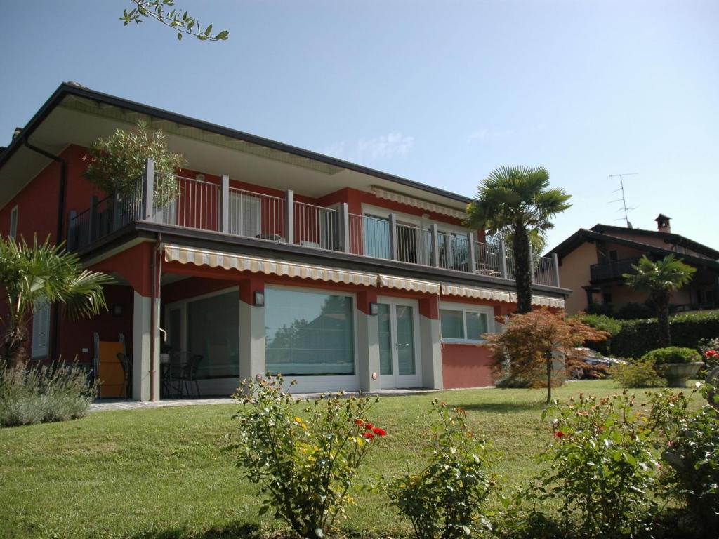 ein rotes Haus mit einer Palme im Hof in der Unterkunft Belvilla by OYO Varese Quattro in Comerio