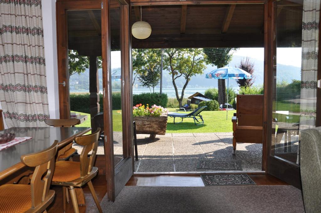 an open door to a patio with chairs and an umbrella at Seebungalows Wedenig direkt am See in Krumpendorf am Wörthersee