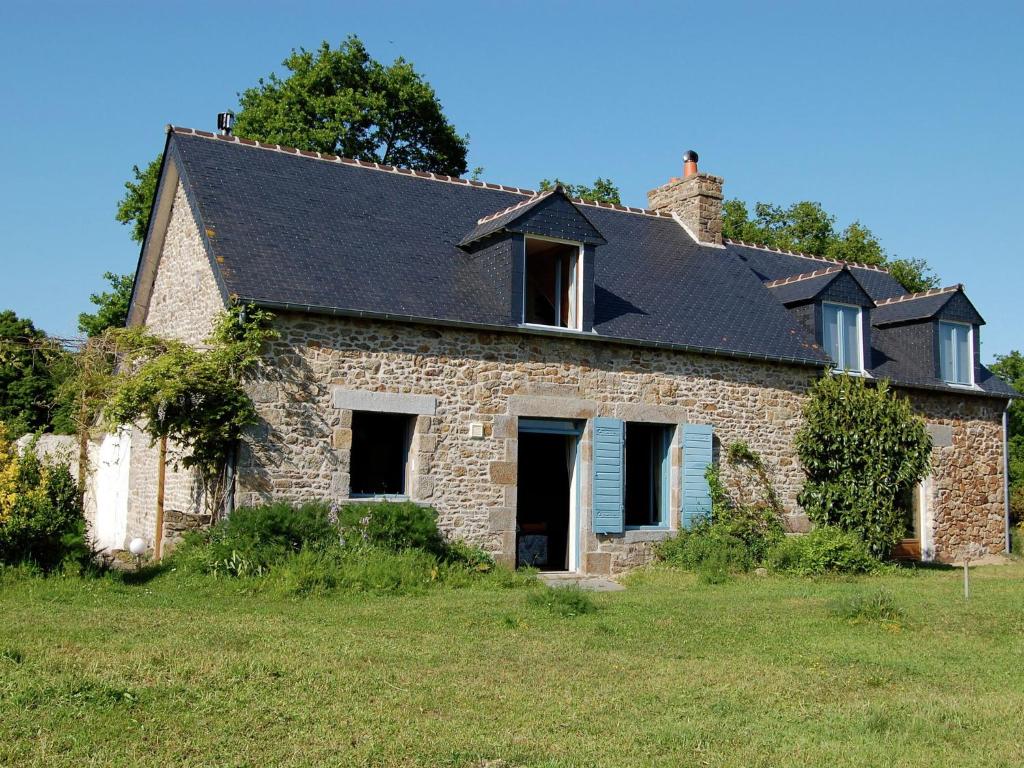 une ancienne maison en pierre avec un toit noir dans l'établissement Lovely mansion with fenced garden, à Baguer-Morvan