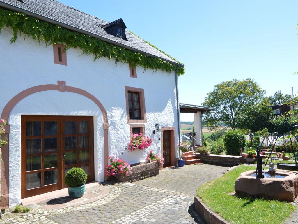 a white house with an archway in front of it at Holiday Home in Ittel with Balcony Heating BBQ Parking in Welschbillig