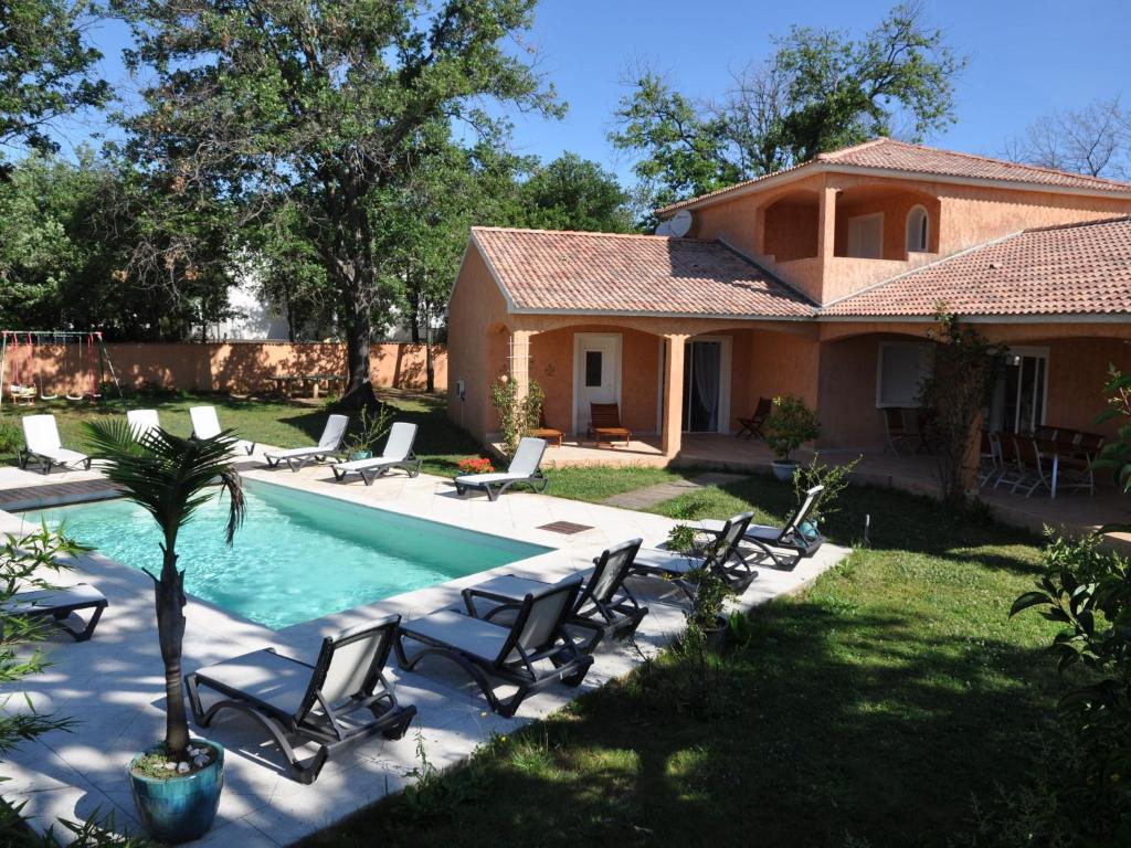 une maison dotée d'une piscine avec des chaises et un palmier dans l'établissement Pleasing Villa near the Sea beach Moriani Plage 5 bedrooms 12 persons, à San-Nicolao