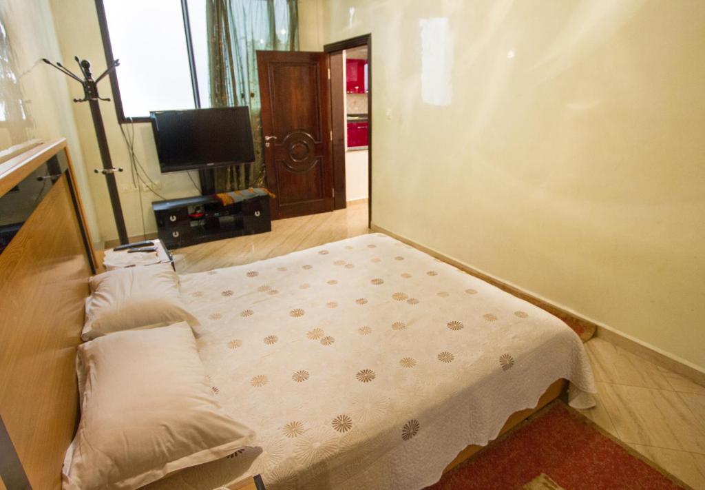 Umbrella Holidays l 1Bd room l في Dcheïra: سرير صغير في غرفة فيها تلفزيون