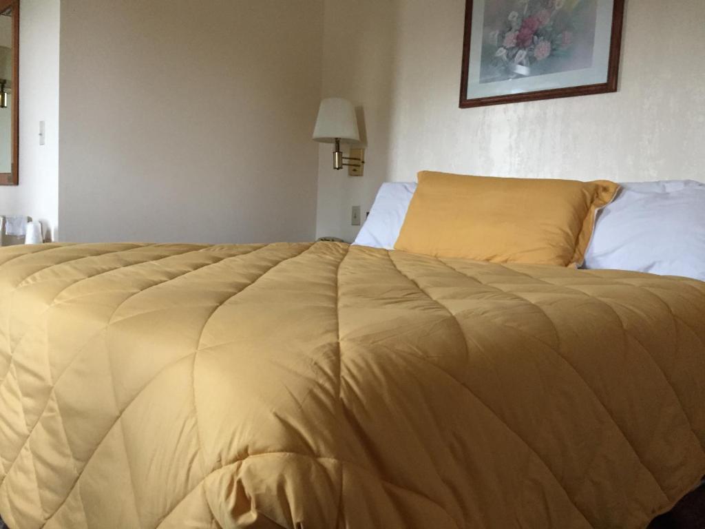 a bed with a yellow comforter in a bedroom at Baxter Inn 4 Less in Baxter Springs
