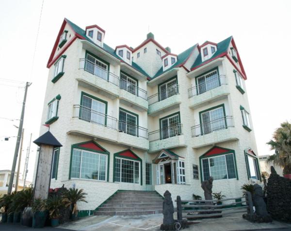 een groot wit gebouw met veel ramen bij Jeju Sea Palace Pension in Jeju-stad