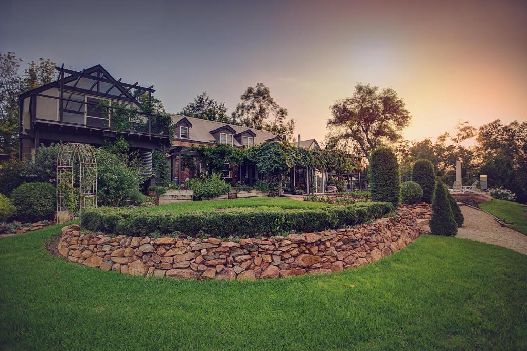 una casa con una pared de piedra y un patio en Evanslea Luxury Boutique Accommodation en Mudgee