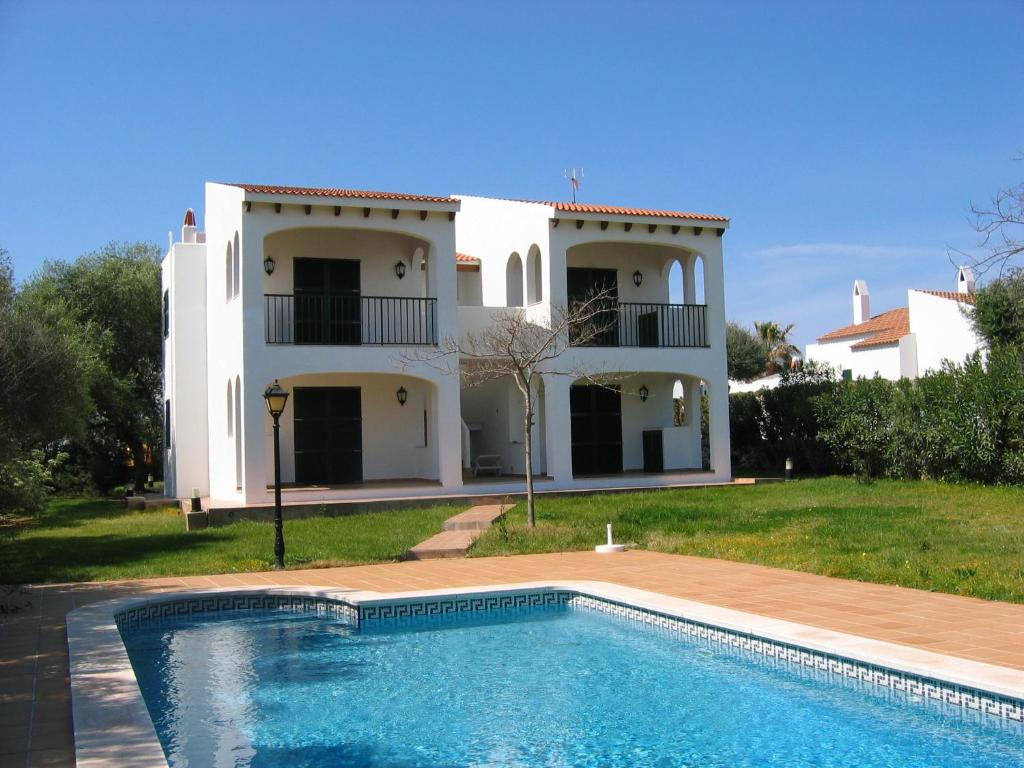 a villa with a swimming pool in front of a house at Apartamentos Marivent in Cala en Blanes