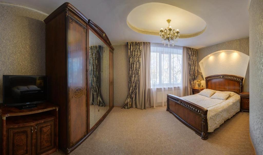 um quarto com uma cama e uma televisão em Ghostinitsa "Lina" em Petropavl