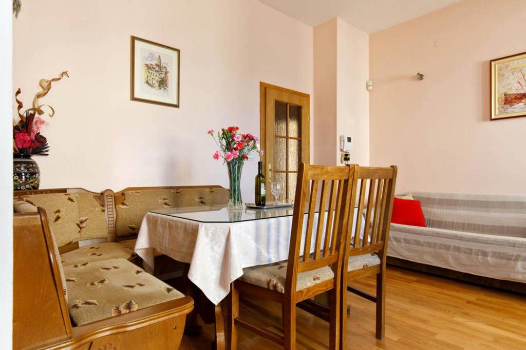 a dining room with a table with a vase of flowers on it at Apartment Ana in Split