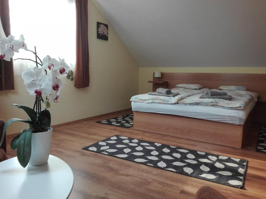 ein Schlafzimmer mit einem Bett und einem Tisch mit einer Blumenvase in der Unterkunft Markal Apartman in Hévíz