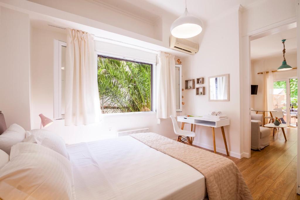 a white bedroom with a large bed and a window at Aloe Apartments in Corfu Town