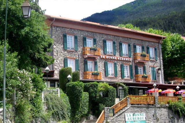 un gran edificio con sombrillas delante en La Bonne Auberge en Saint-Martin-Vésubie