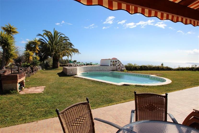 Los Carrizales的住宿－Apartment Colibri Finca Montimar，一张桌子和两把椅子以及一个游泳池