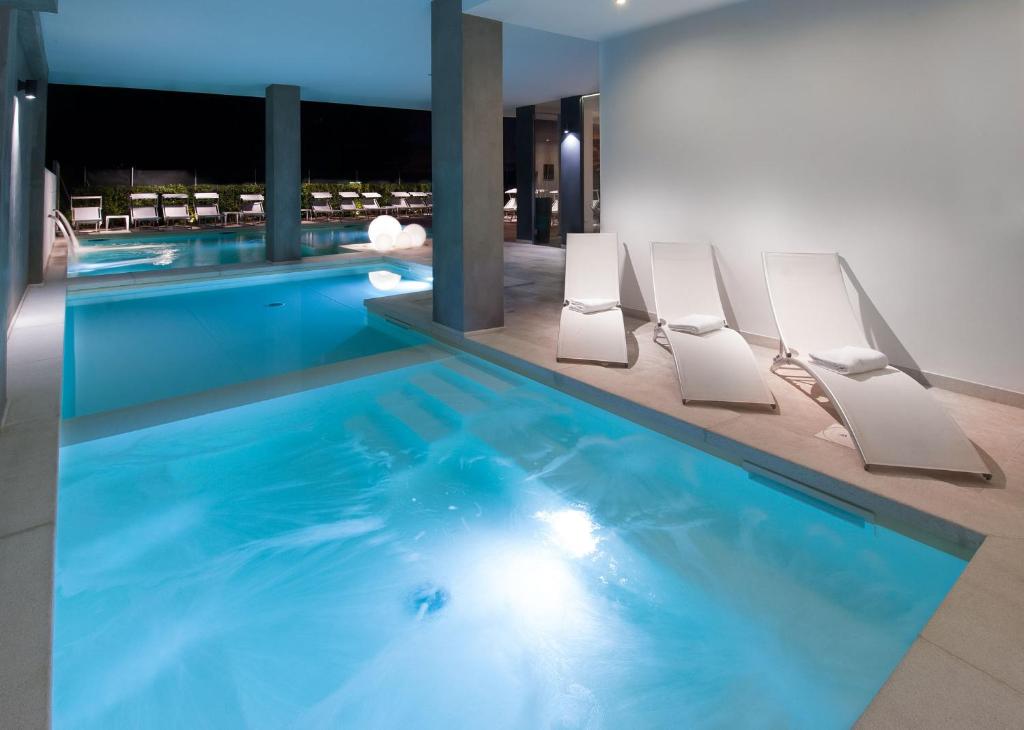 una grande piscina con sedie bianche in un edificio di Hotel Niagara a Cattolica