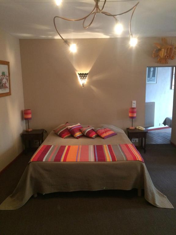 a bedroom with a large bed with colorful pillows at Hotel Vidal in Céret