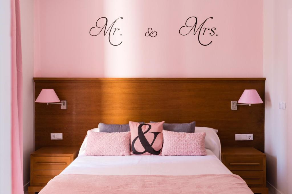 a bedroom with a bed with pink pillows and the words me and mis at Imperial Mérida in Merida