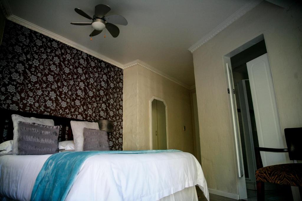 una camera da letto con un letto e un ventilatore a soffitto di Princes Lodge Guesthouse a East London