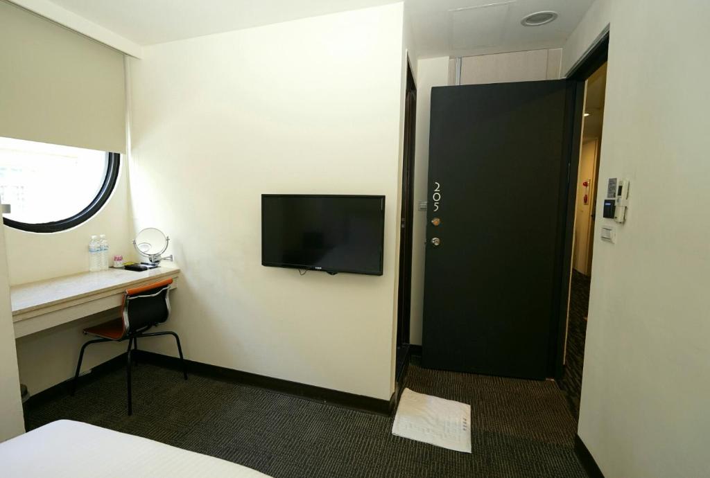 a room with a tv and a desk and a door at Century Hotel in Kaohsiung