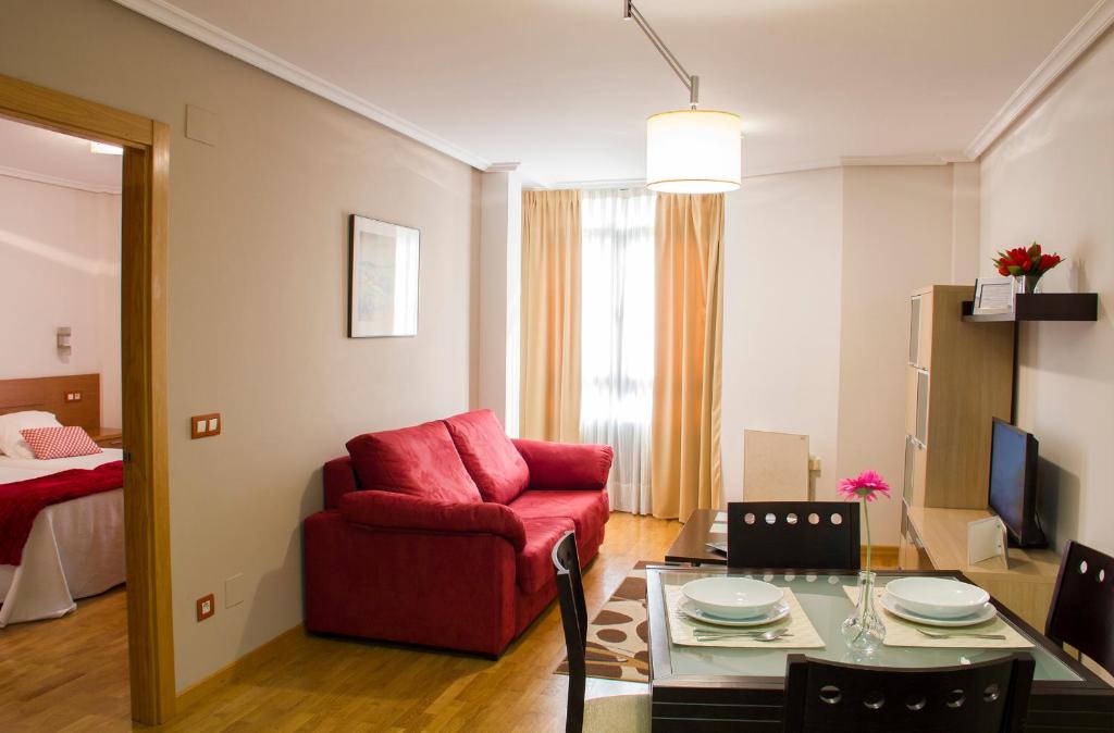 ein Wohnzimmer mit einem roten Stuhl und einem Tisch in der Unterkunft Apartamentos Cean Bermudez in Gijón