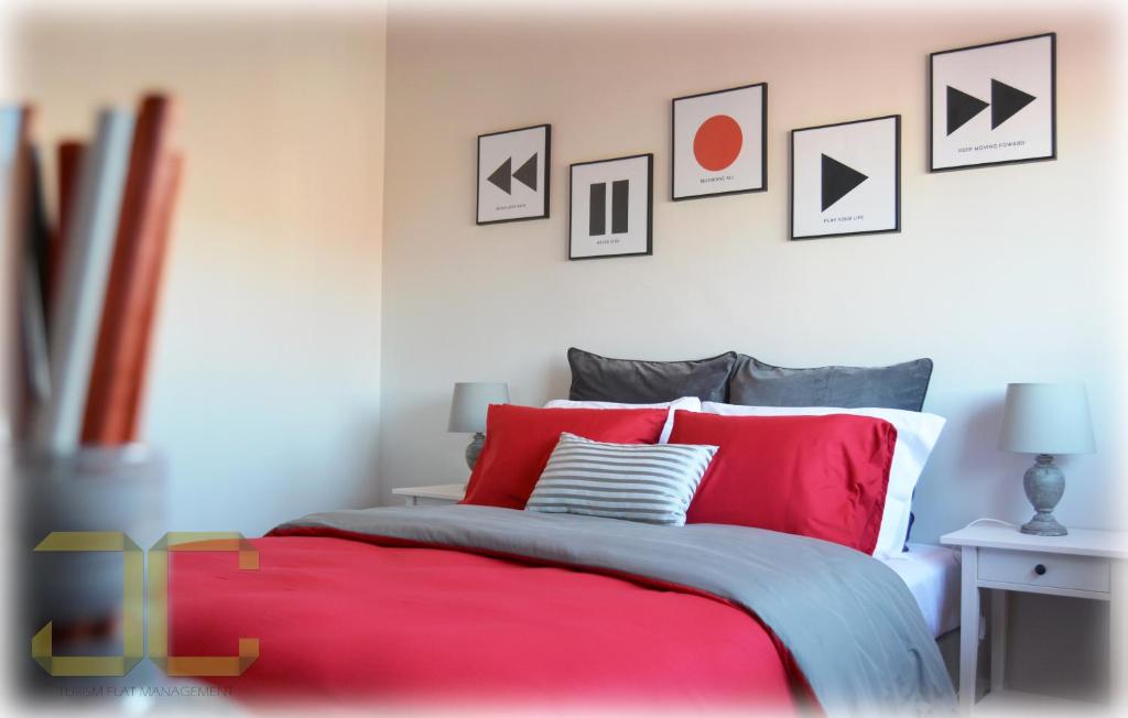 a bedroom with a red bed with pictures on the wall at Country Apartment by JC in Porto