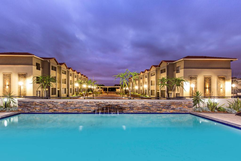 uma piscina em frente a um hotel à noite em Savannah Park Luxury Apartments em Durban