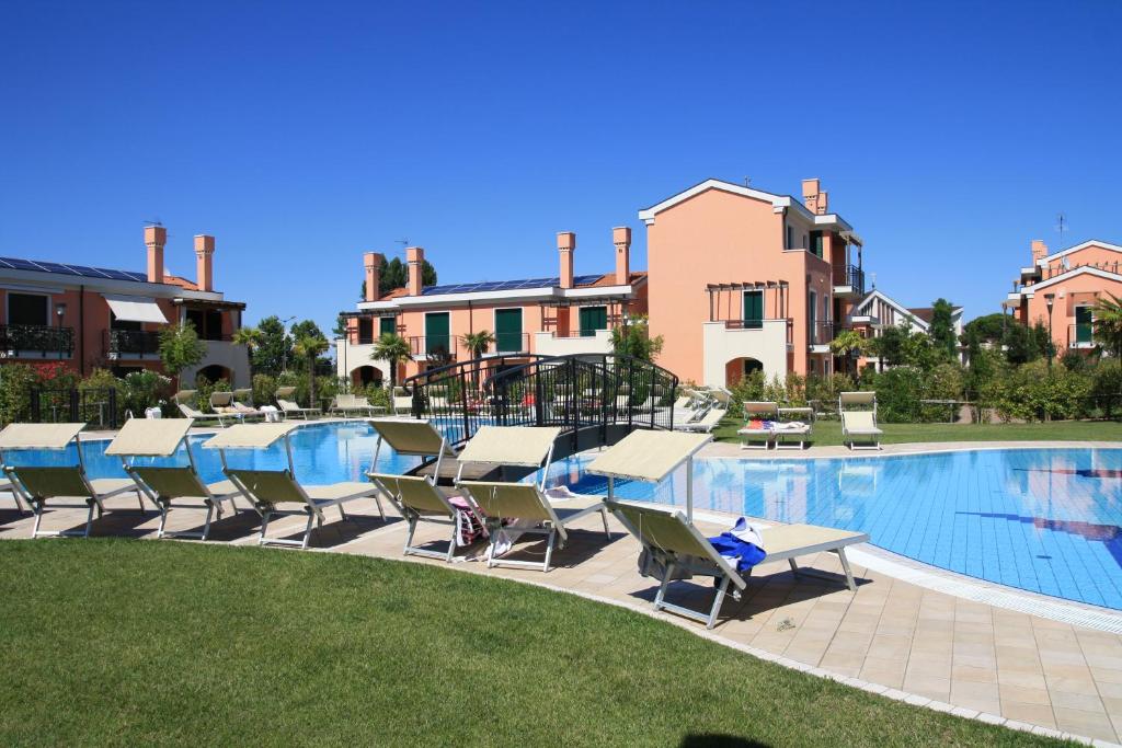 una piscina in un resort con sedie e tavolo di Milano Dune Family Apartment a Lido di Jesolo