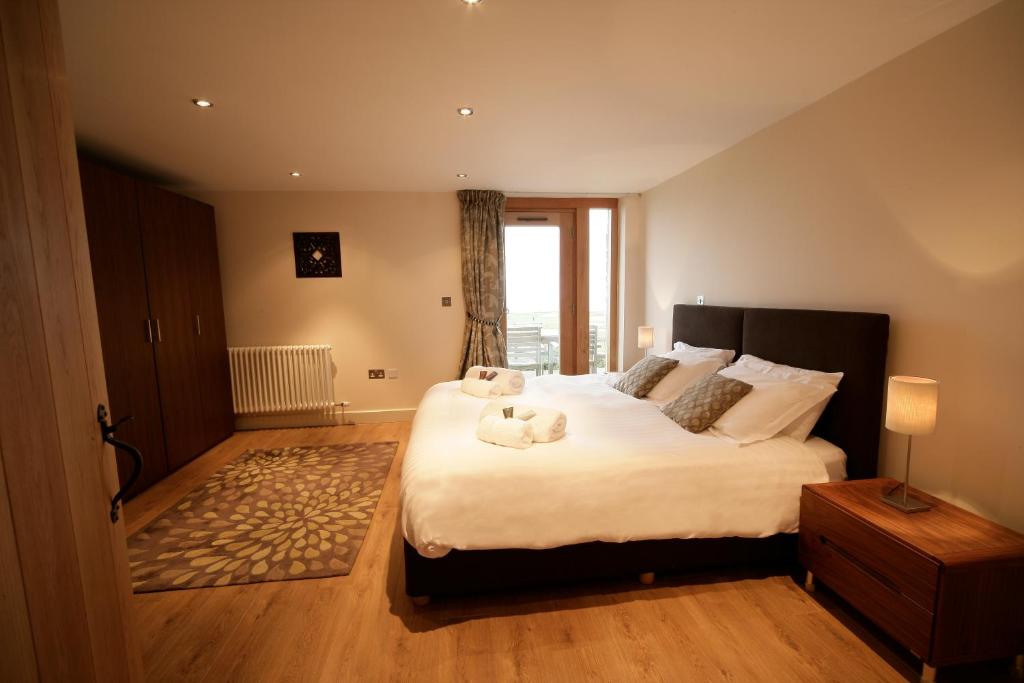 a bedroom with a large bed with two stuffed animals on it at The Stables 1 - Llyn Peninsula in Nefyn