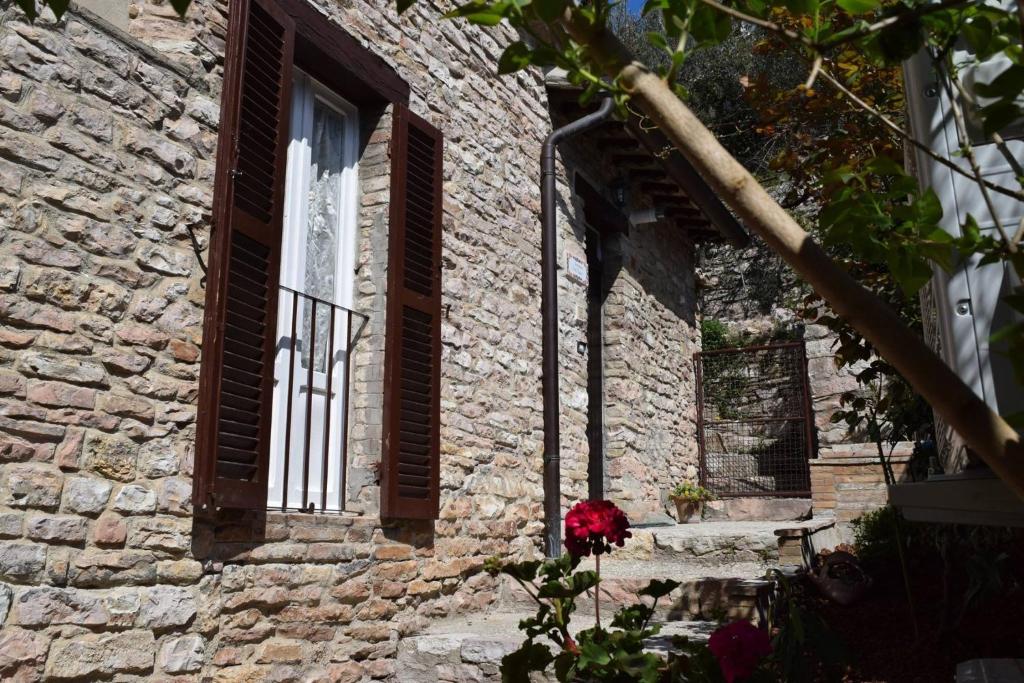 een bakstenen gebouw met een raam en een rode roos bij Apartments Aurora Delle Rose in Assisi