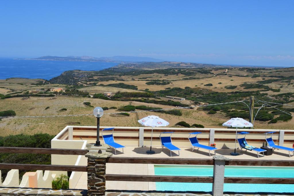 - une piscine avec chaises longues et parasols et l'océan dans l'établissement Agriturismo Finagliosu, à Palmadula